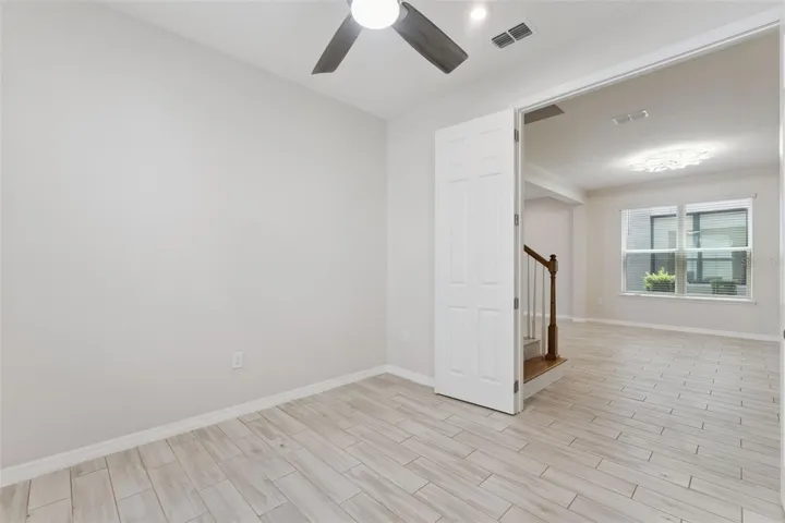 Downstairs Study – Bright, versatile main-level study with neutral finishes, tile flooring, a ceiling fan, and natural light, offering flexible space for a home office, reading room, or creative workspace.