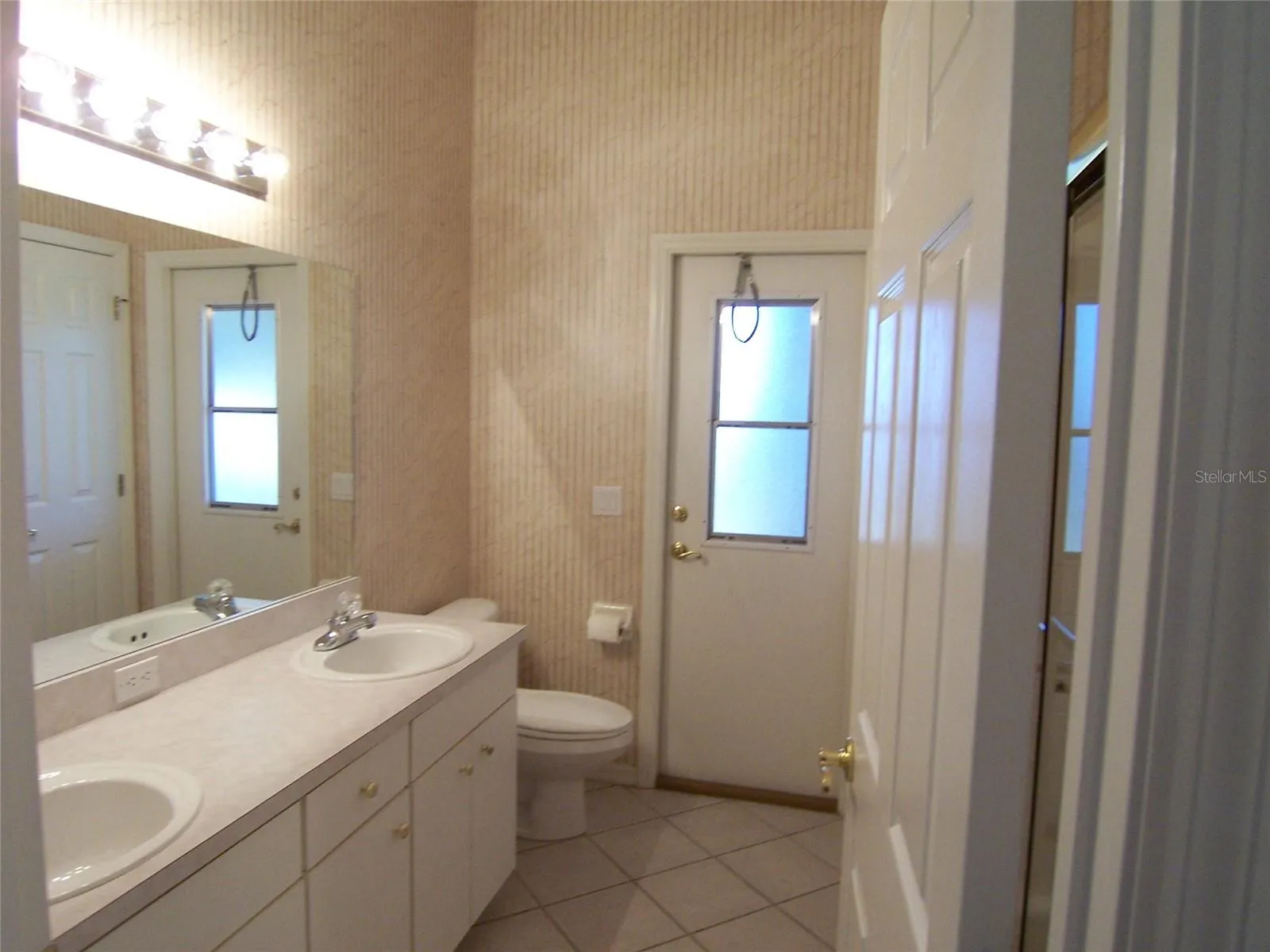 BATH 2 - dual sinks - tub/shower and linen closet - DOOR LEADS OUT TP SCREENED LANAI  Wallpaper being removed
