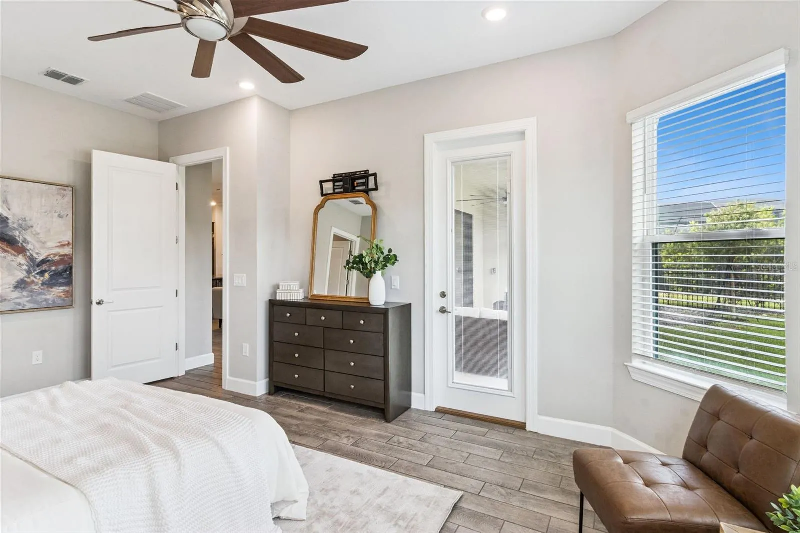 First primary bedroom with ceiling fan and window views.