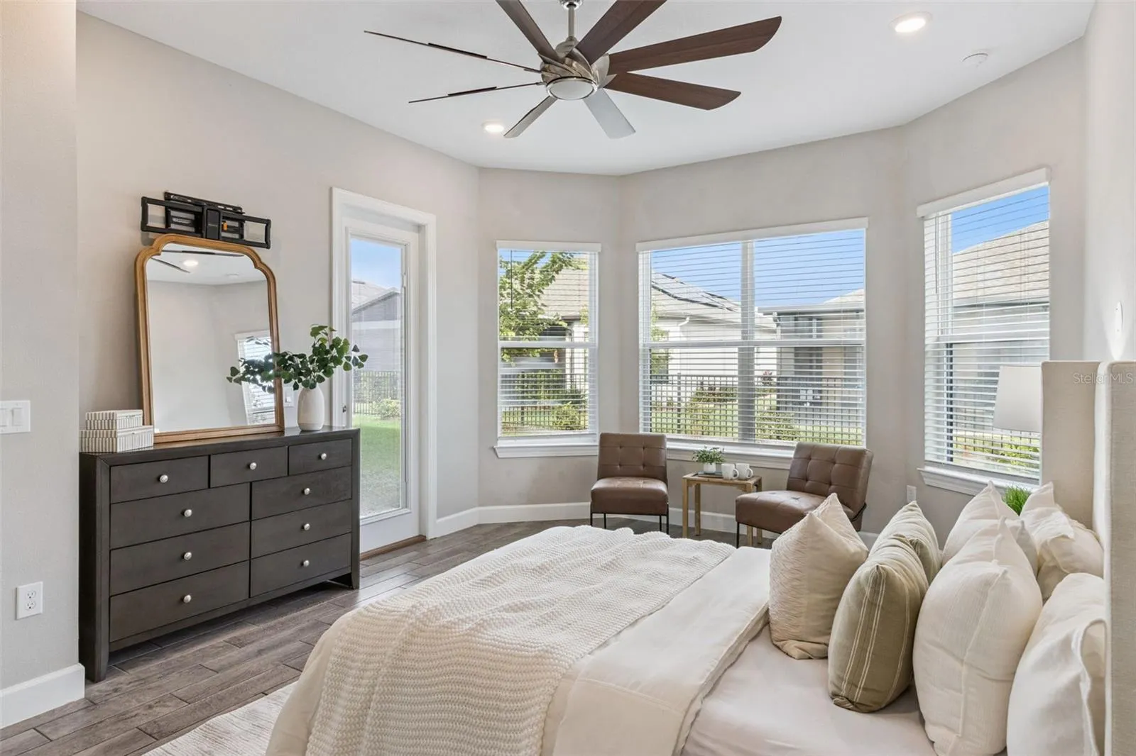 First primary suite with bay window sitting area, ceiling fan, and room for a king bed.
