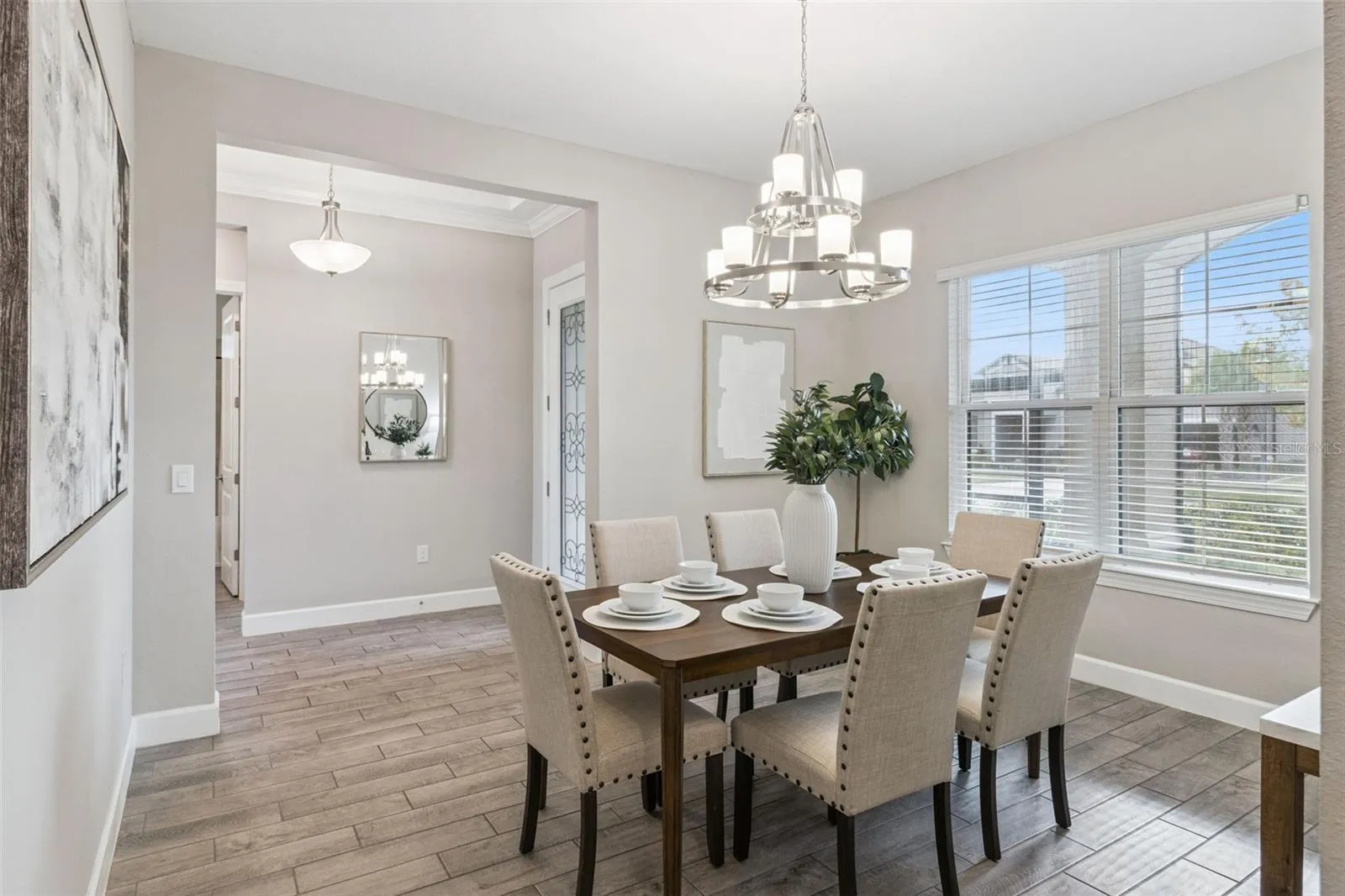 Separate dining room with elegant chandelier, neutral finishes, and natural light.