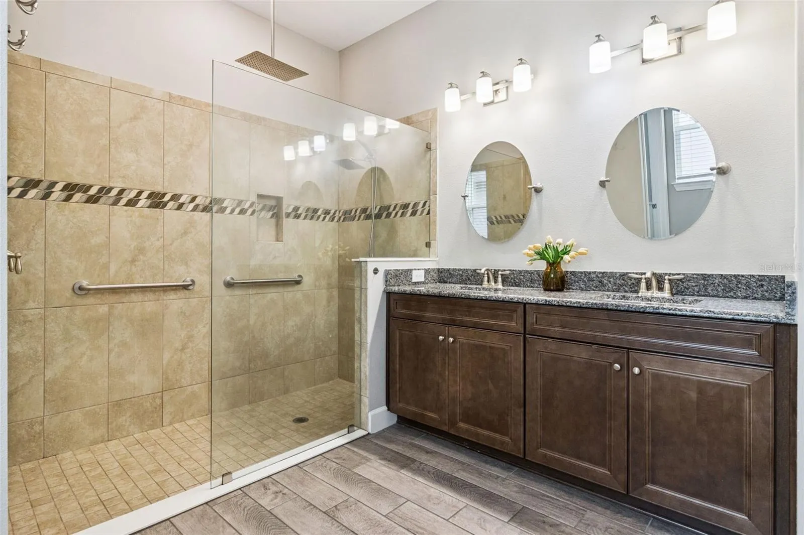 First primary bathroom with dual sink vanity, granite counters, and glass enclosed walk in shower.