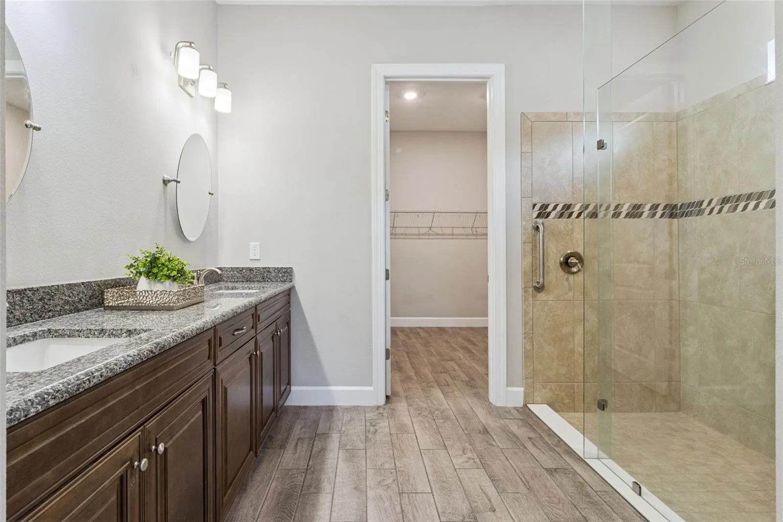 Second primary bathroom with granite vanity, tiled walk in shower, and walk in closet.