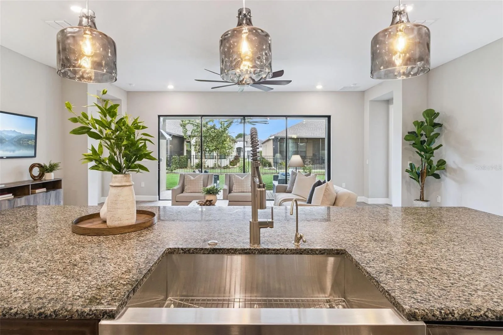 View from the kitchen sink across granite counters to the living area and covered patio.