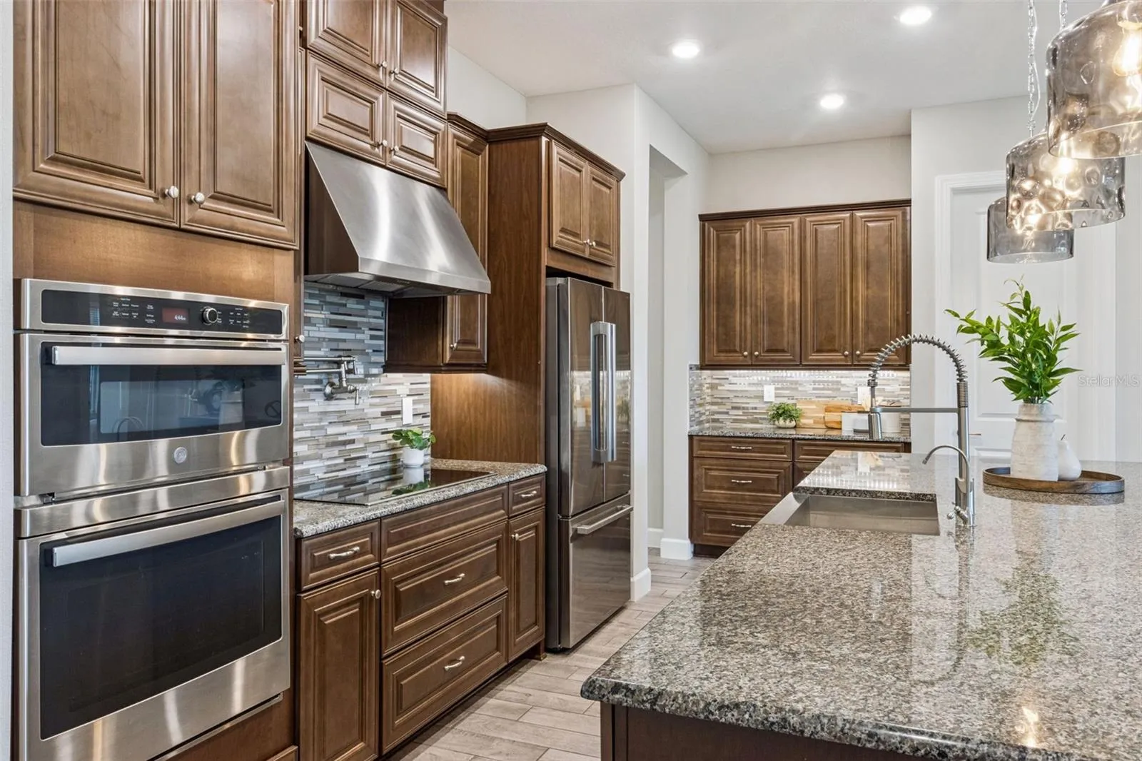 Kitchen with double wall ovens, stainless steel refrigerator, and solid wood cabinetry.