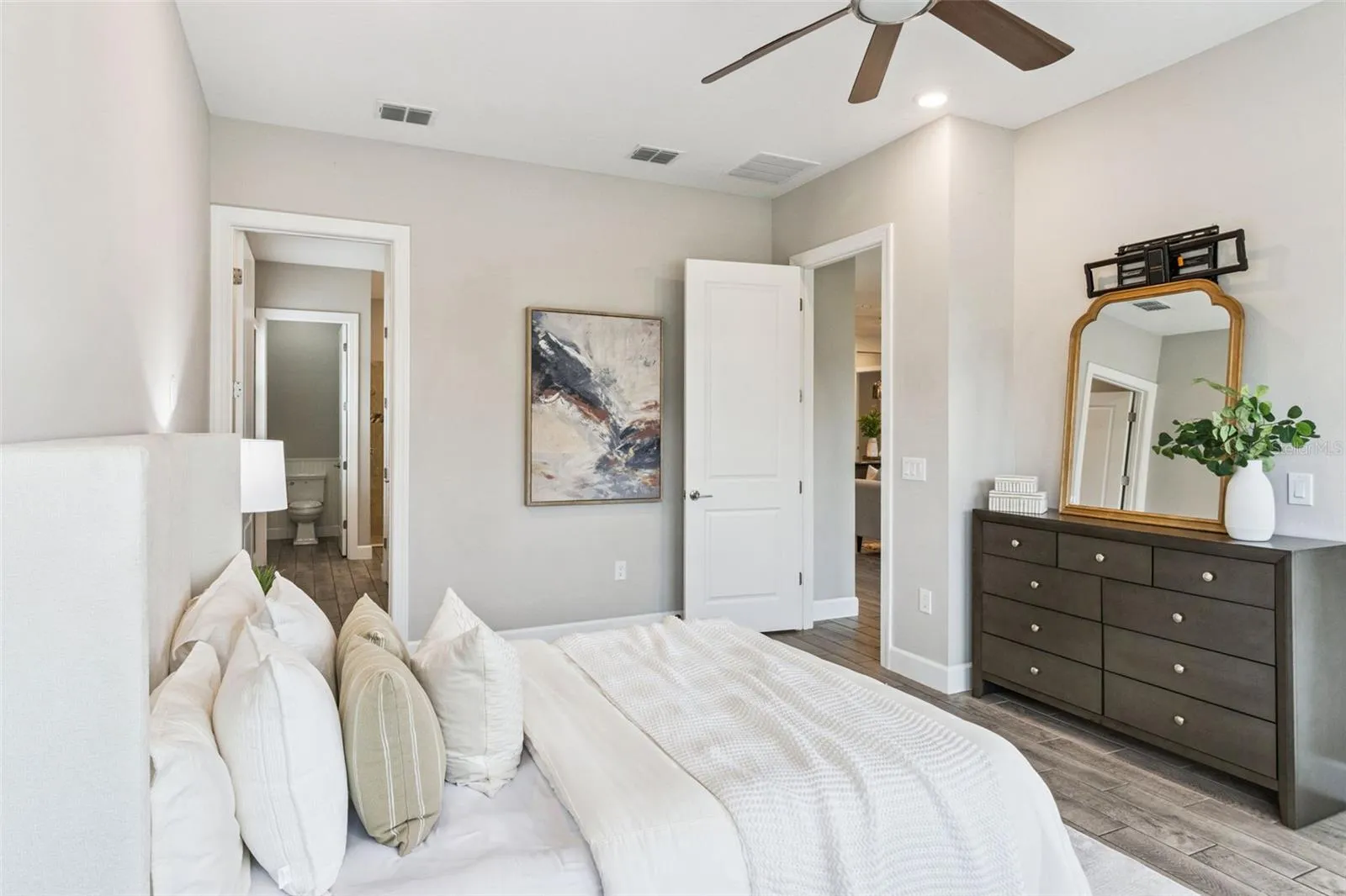 First primary bedroom with dresser area, ceiling fan, and generous space.