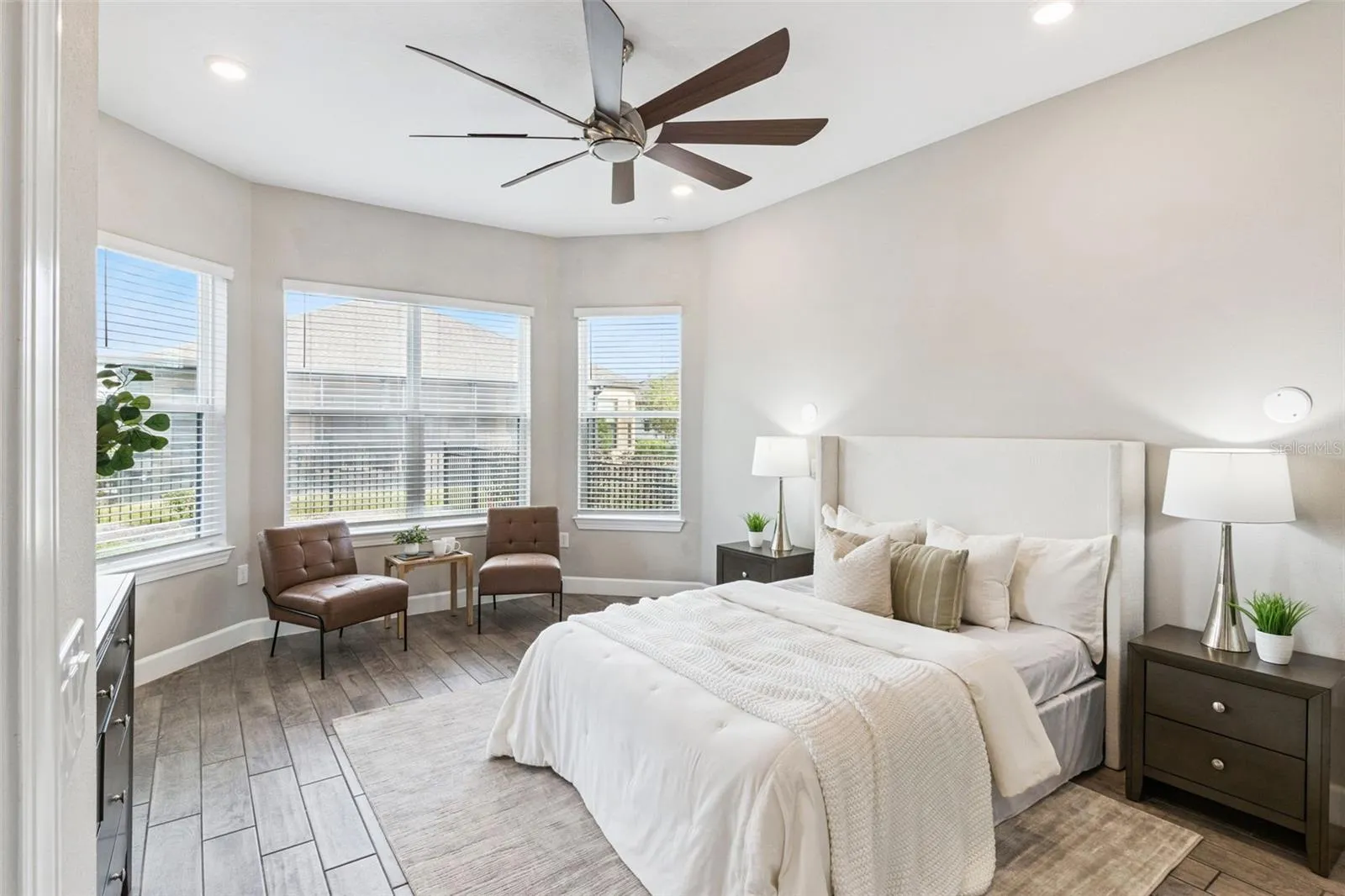 First primary bedroom with bay windows, ceiling fan, and abundant natural light.