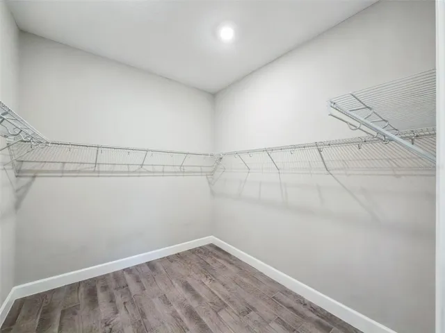 Walk in closet in the second primary suite with shelving and hanging space.