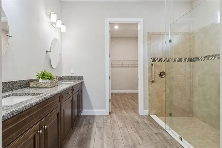 Second primary bathroom with granite vanity, tiled walk in shower, and walk in closet.