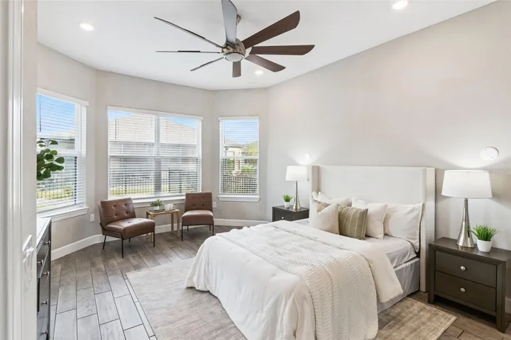First primary bedroom with bay windows, ceiling fan, and abundant natural light.
