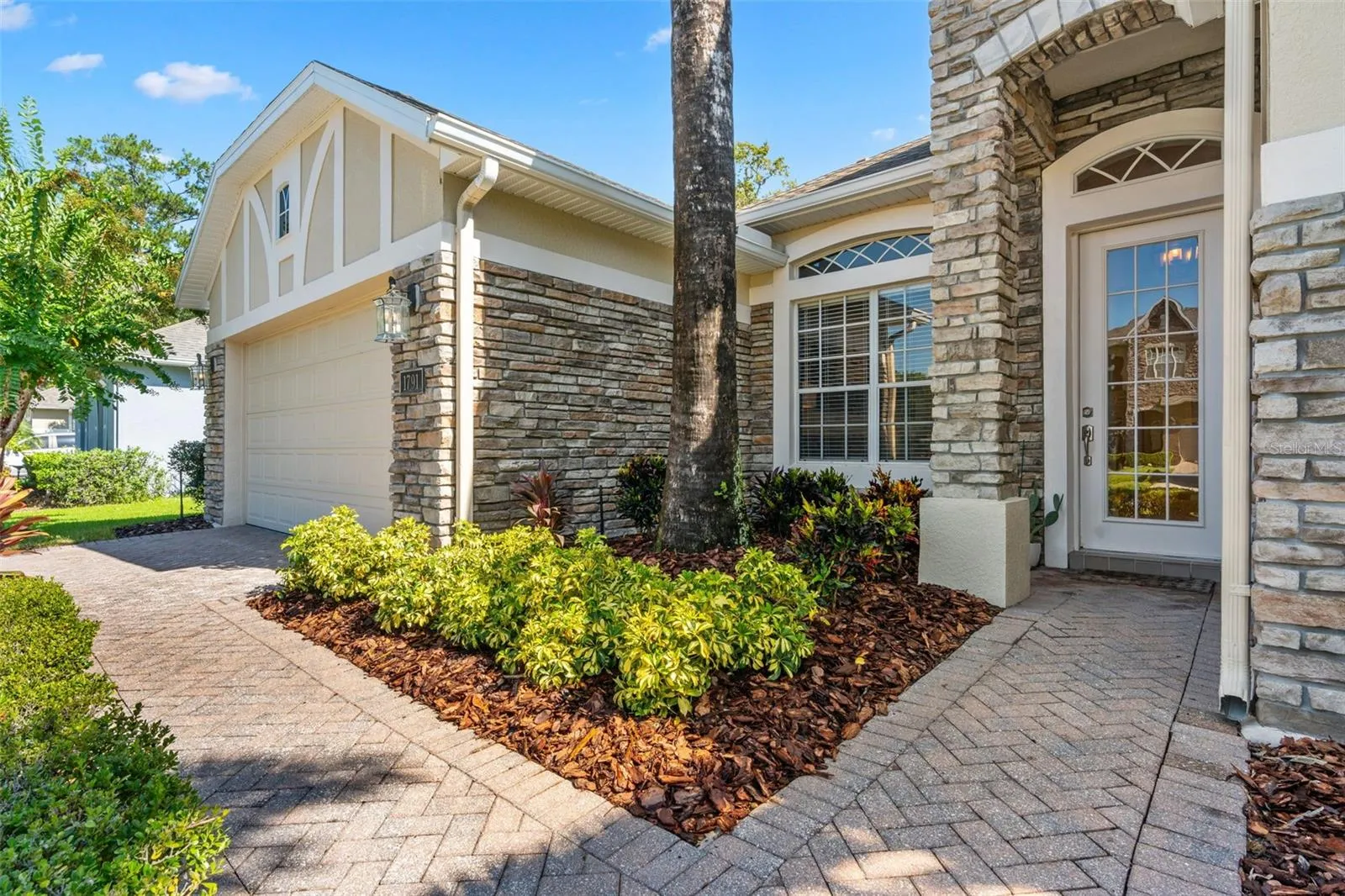 FRESH LANDSCAPING (2026), STONE-FACED ACCENTS and a BRICK-PAVER walkway lead to the beautiful GLASS-PANELED FRONT DOOR.