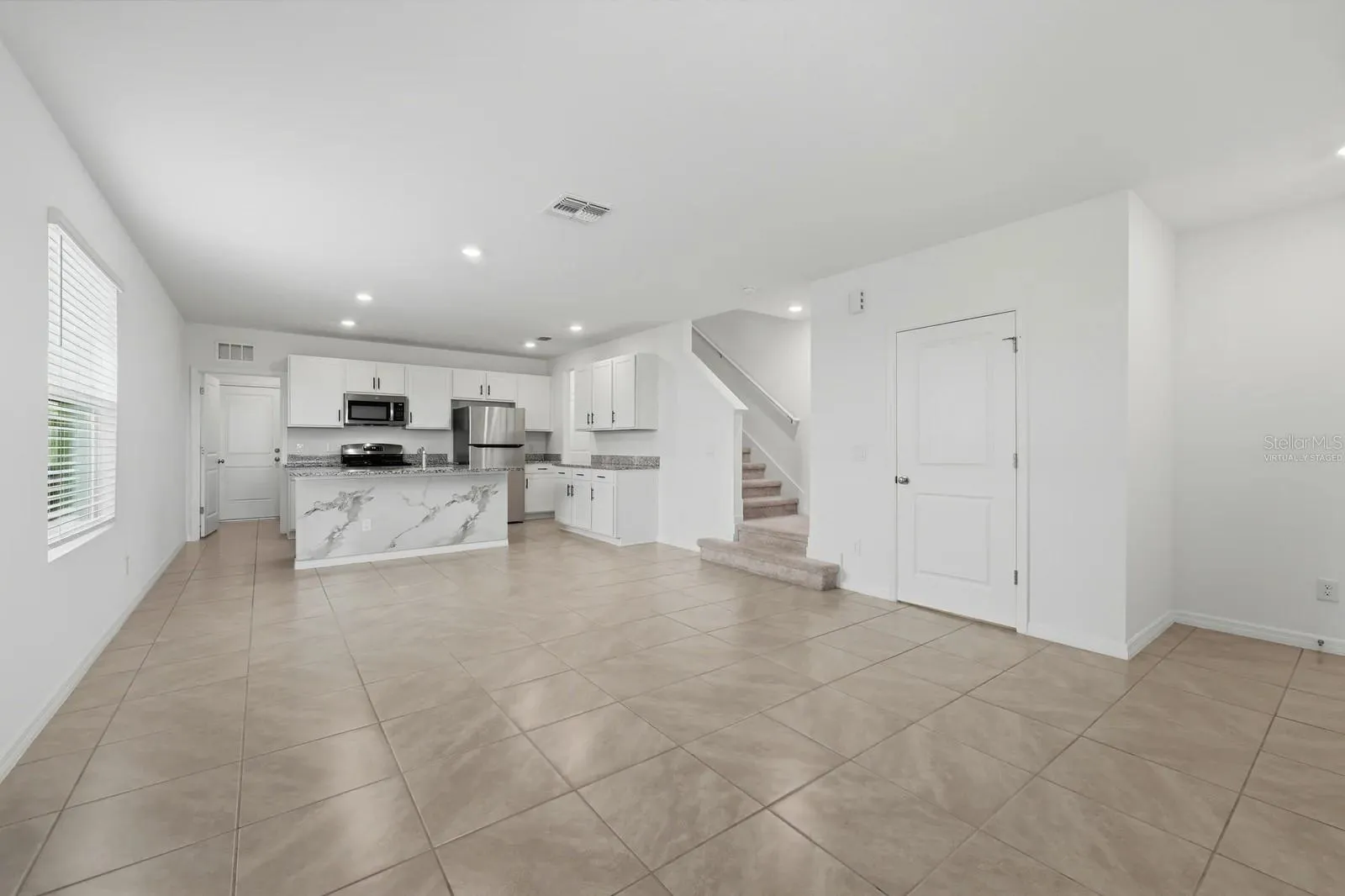 Virtually staged living room illustrating potential furniture layout kitchen island