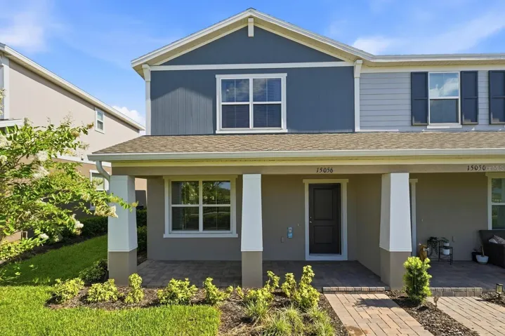 Front exterior of this desirable end-unit townhome featuring a covered entry, paver walkway, and modern façade