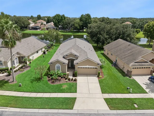 Front Aerial / Opening Photo – Welcome to 9154 Pecky Cypress Way, where an inviting single-story home, manicured landscaping, and a picturesque pond setting create a memorable first impression.