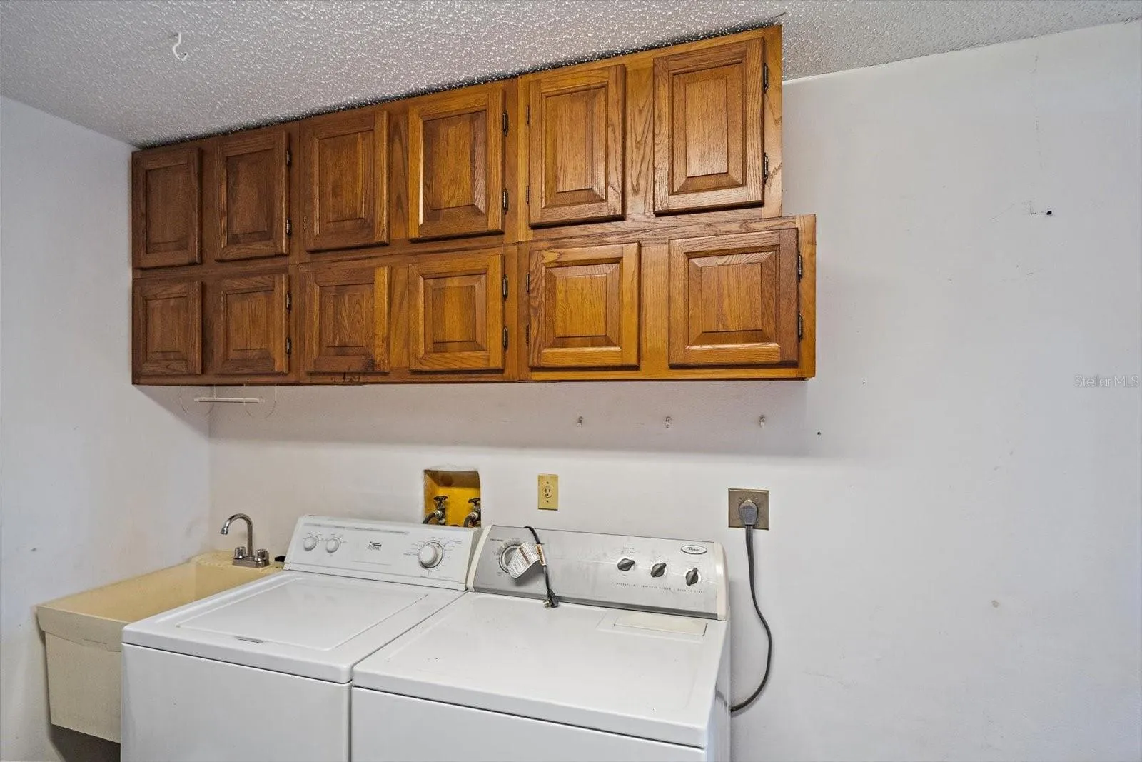 Laundry in garage with additional storage and utility sink