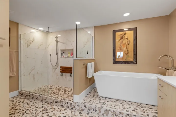 Teak fold down shower seat, frameless glass shower with multiple shower heads,  soaking tub