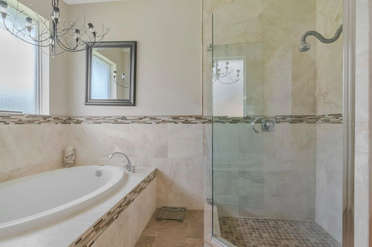 Soaking Tub with separate walk in shower featuring travertine