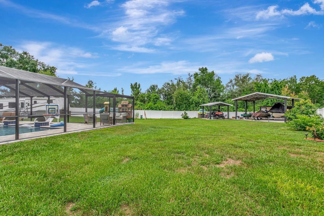 View of Backyard, Playground, Two Covered Open-Air Structured Storage areas with Concrete Pads, Firepit, and Shed. Bring the Boat- Bring the Toys - There's room for everything!