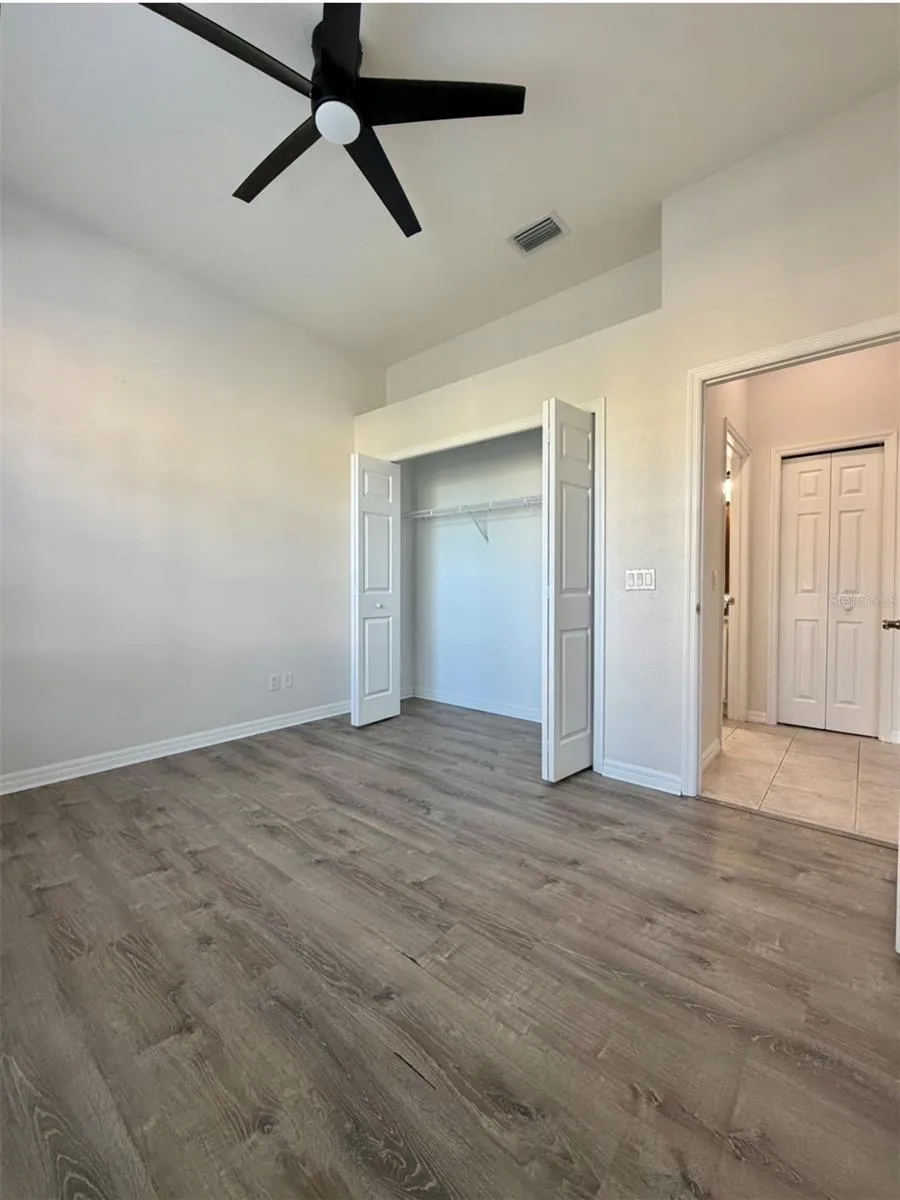 Bedroom 2 faces the front of the home, and it features LVP flooring, a ceiling fan, and an extra-wide closet.