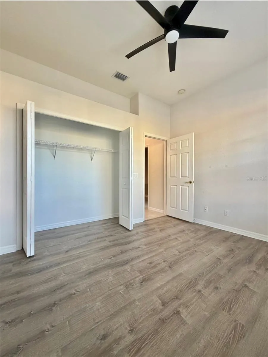 Bedroom 2 faces the front of the home, and it features LVP flooring, a ceiling fan, and an extra-wide closet.