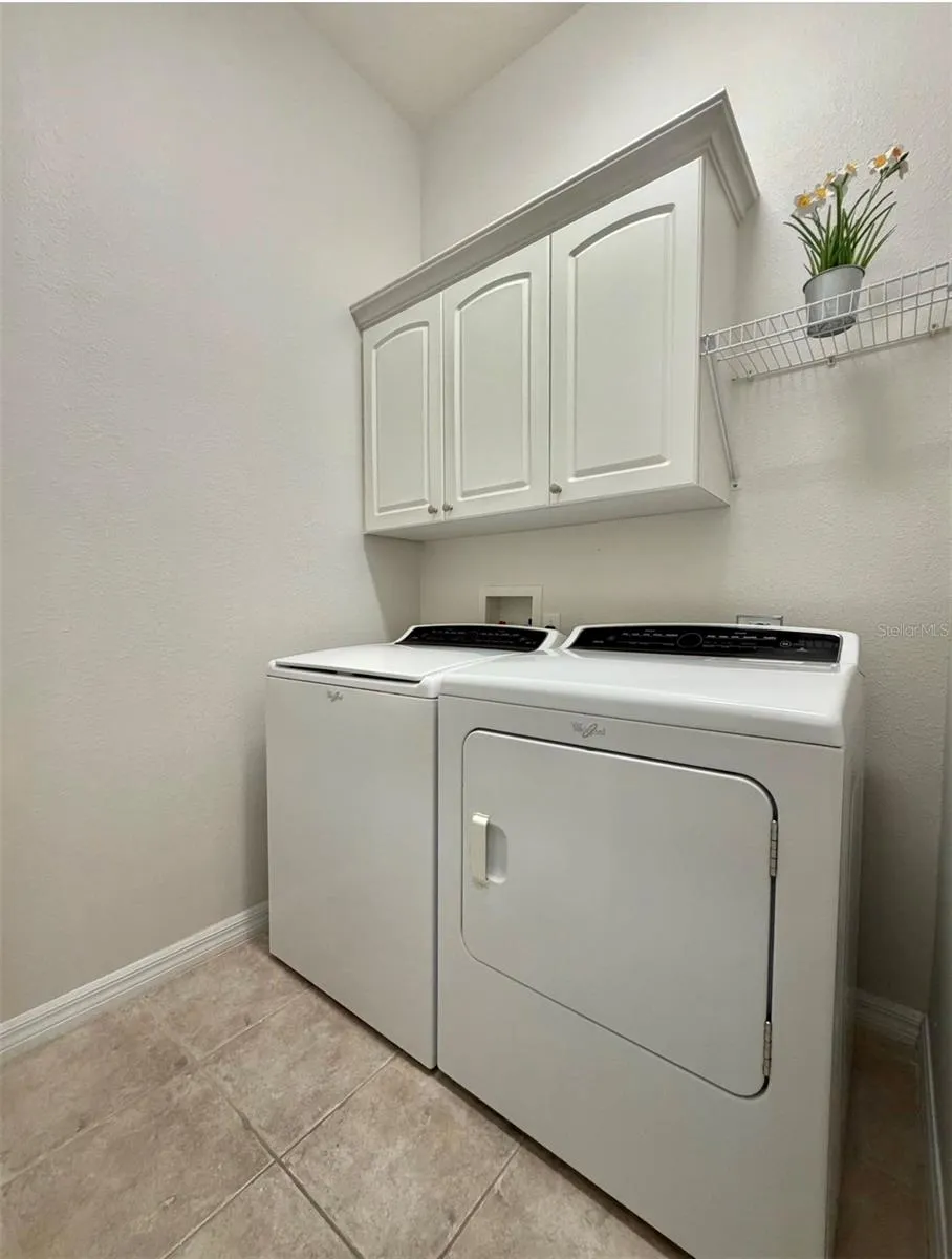 The laundry room is so spacious and features cabinet storage, shelf storage, and space for more shelves too.