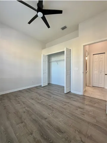 Bedroom 2 faces the front of the home, and it features LVP flooring, a ceiling fan, and an extra-wide closet.