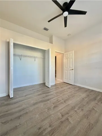 Bedroom 2 faces the front of the home, and it features LVP flooring, a ceiling fan, and an extra-wide closet.