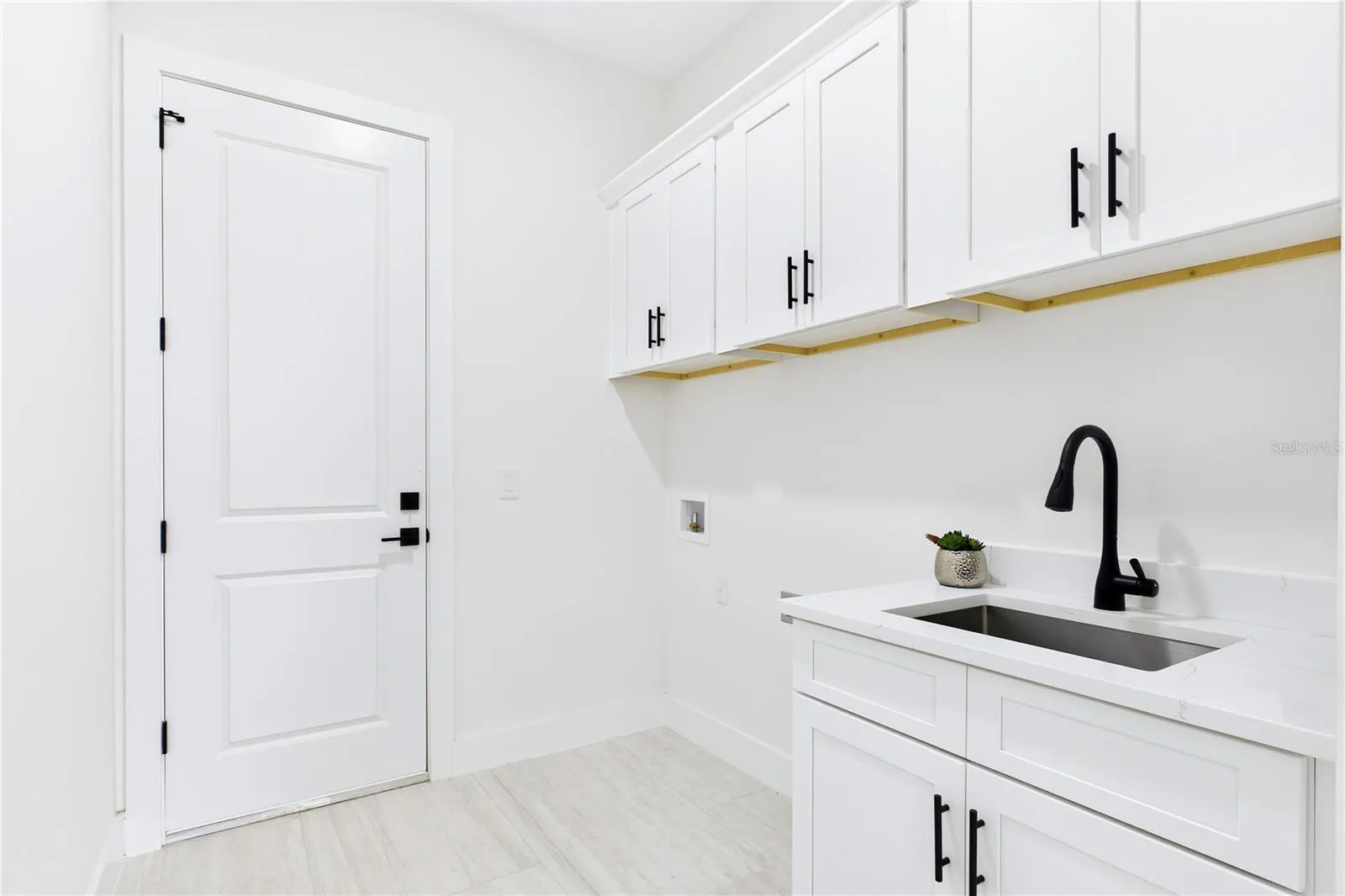 FUNCTIONAL LAUNDRY ROOM combines style &amp; convenience w/ QUARTZ countertops, utility sink &amp; abundant built-in cabinetry for effortless organization!