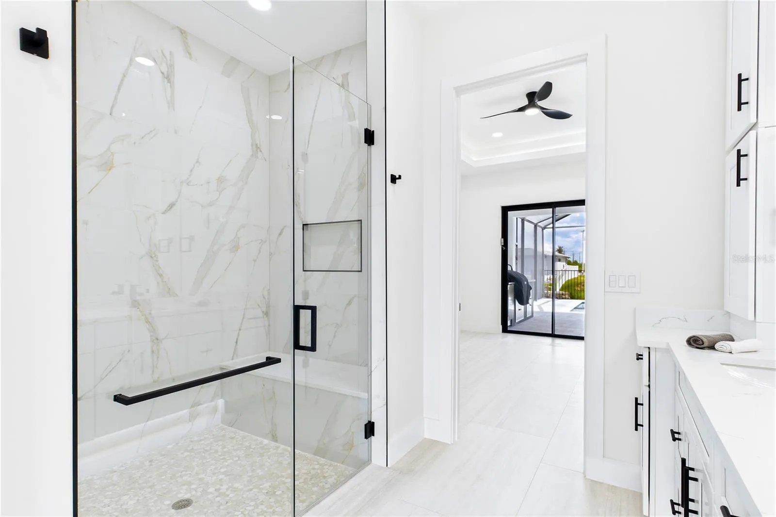 LUXURIOUS PRIMARY BATHROOM w/ spacious WALK-IN GLASS SHOWER w/ floor-to-ceiling designer tile, rainfall showerhead, built-in bench &amp; modern matte-black fixtures