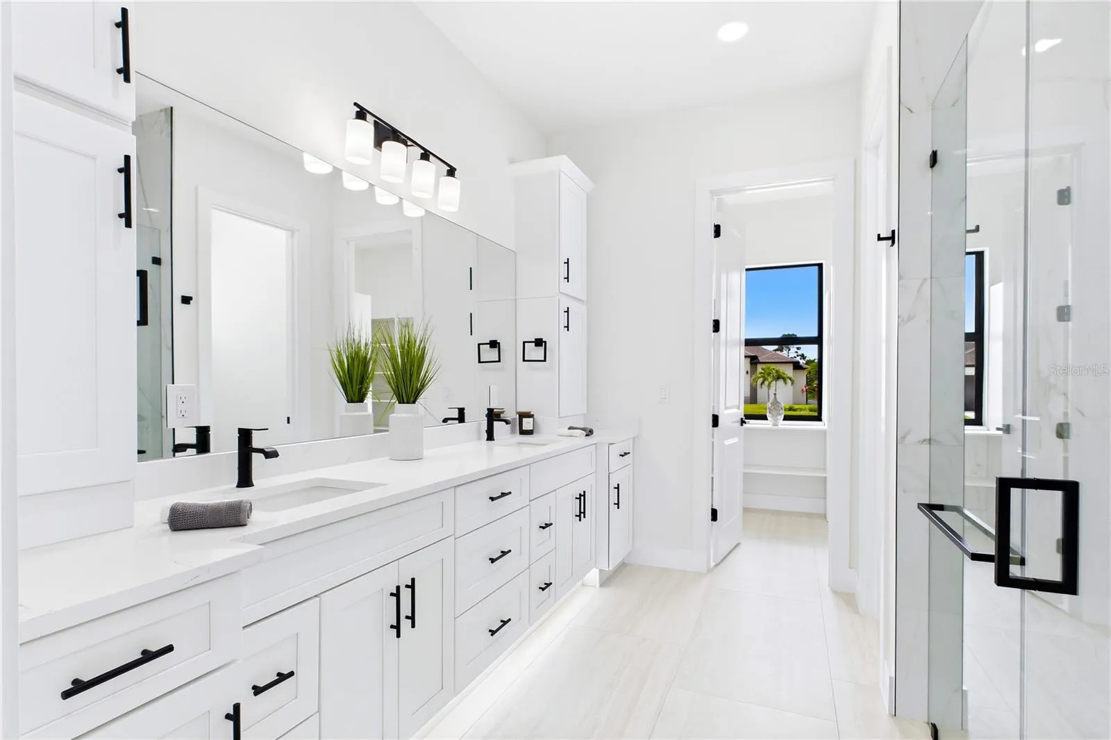 Dual sink vanity w/ quartz countertops, sleek white cabinetry &amp; contemporary lighting complements the spa-like design