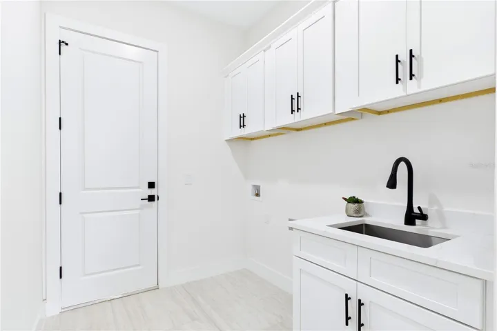 FUNCTIONAL LAUNDRY ROOM combines style &amp; convenience w/ QUARTZ countertops, utility sink &amp; abundant built-in cabinetry for effortless organization!
