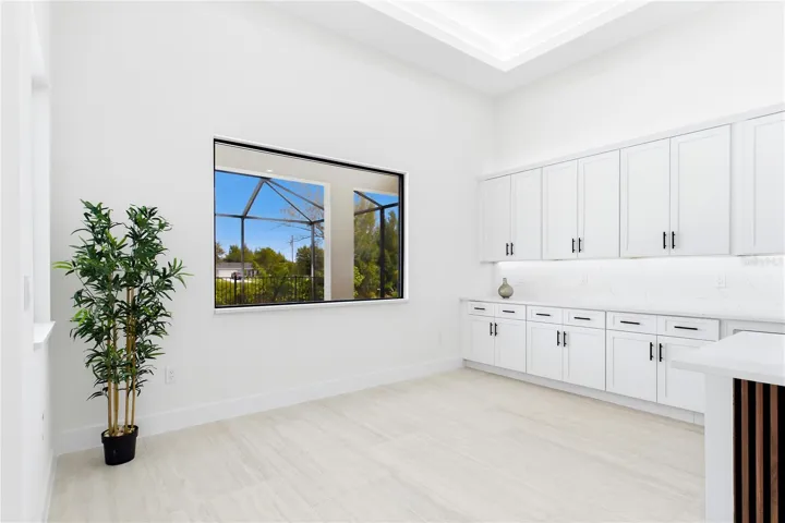 DINING ROOM features a soaring volume ceiling, recessed LED lighting &amp; LARGE PICTURE WINDOW to screened lanai, pool/spa &amp; waterfront.
