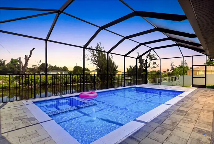 Step outside to SCREENED LANAI w/ HEATED POOL &amp; SPA, landscape, SEAWALL &amp; FULLY EQUIPED OUTDOOR KITCHEN