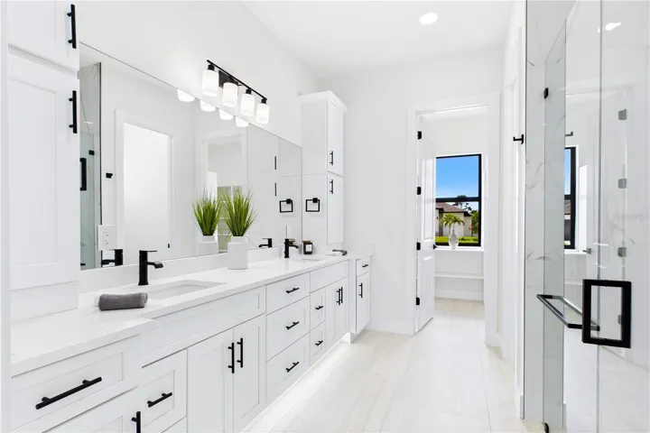 Dual sink vanity w/ quartz countertops, sleek white cabinetry &amp; contemporary lighting complements the spa-like design