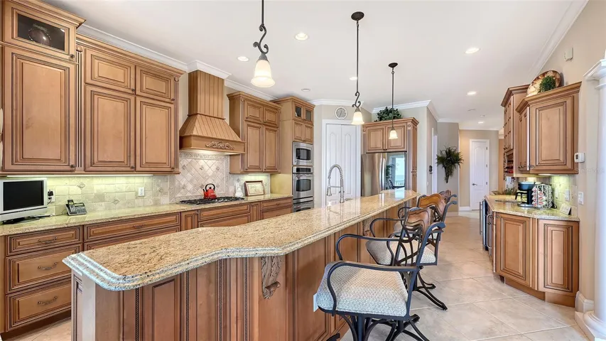 Gorgeous kitchen with wood cabinetry, granite counter tops, GE Profile and LG appliances. Gas stove, double oven, walk-in pantry is behind the white doors Coffee bar area with wet sink and two wine/beverage refrigerators on right.