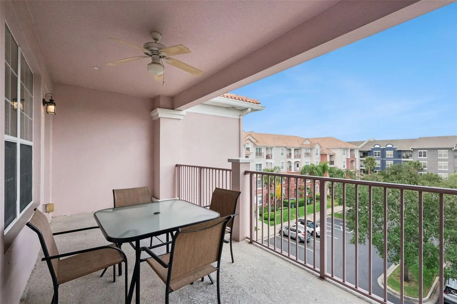 Balcony Dining Area:Covered outdoor living space featuring a glass-top dining table, overhead fan, and open views of the lush resort surroundings.