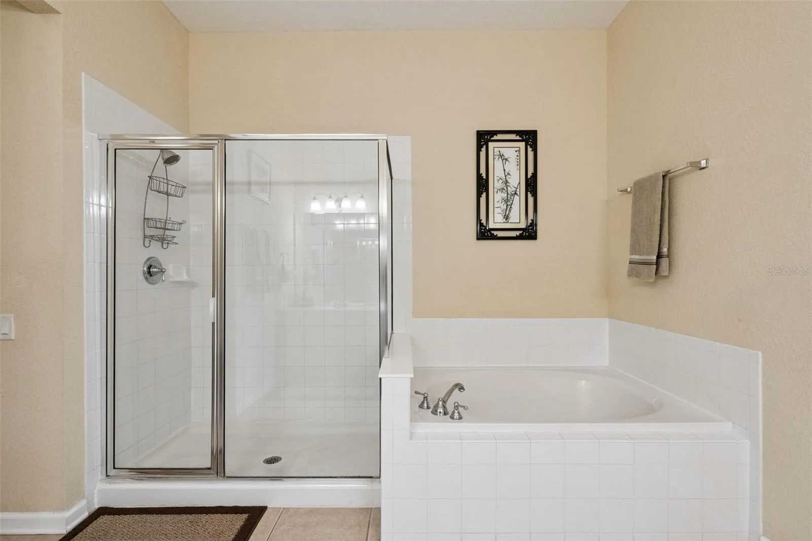 Soaking Tub & Glass Shower:Primary bathroom features highlighting a separate glass-enclosed step-in shower stall and a deep soaking tub framed by white tile work.