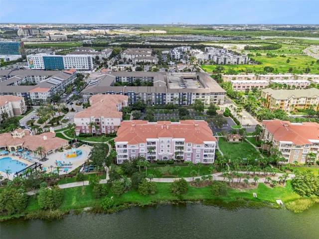 Building & Lakefront Aerial:Direct aerial overview of the building's lakefront position, adjacent pool complex, manicured lawn, and surrounding Orlando skyline.