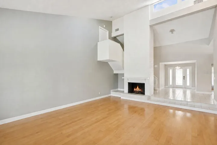 Inviting foyer and family room featuring a floor-to-ceiling brick fireplace, skylights that fill the space with natural light, and a staircase leading to three spacious upstairs bedrooms.