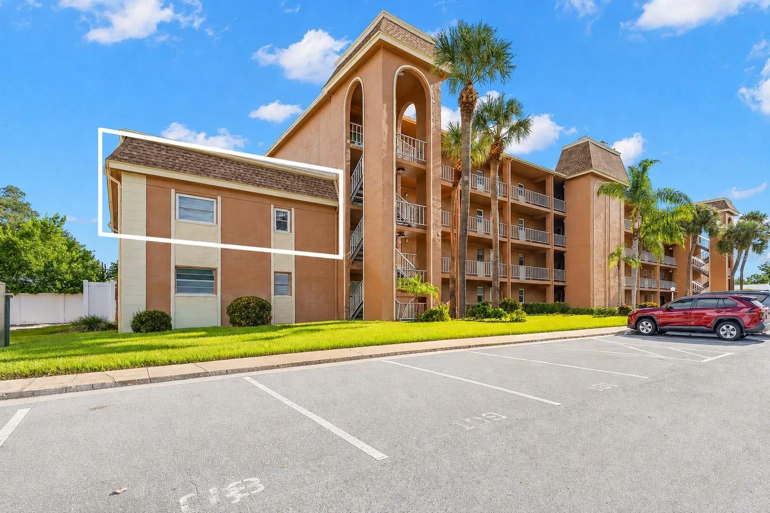 Tucked into the end section of the building, the outlined residence enjoys a more private position with no neighbors above, while mature palms and landscaped grounds frame the community setting.