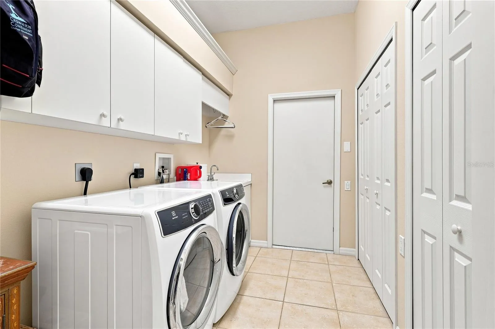 Spacious laundry room with utility sink, upper cabinetry and generous storage