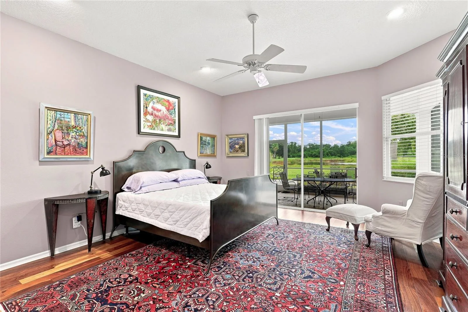 Spacious primary bedroom with hardwood floors, high ceilings and direct lanai access with peaceful backyard views