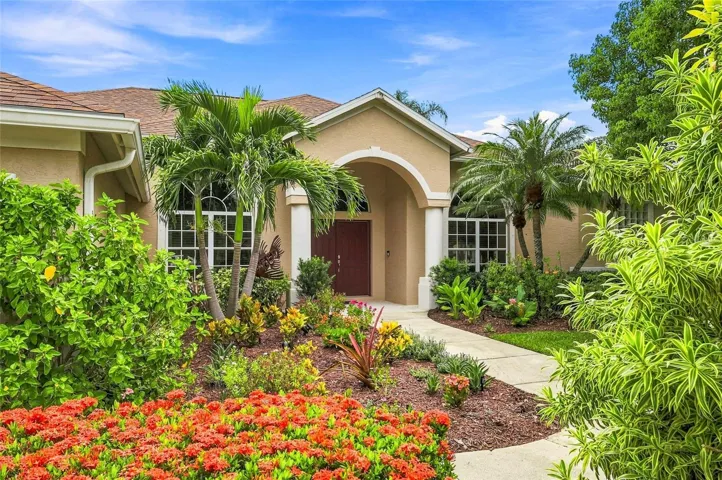 A warm welcome begins with lush tropical landscaping and a beautifully maintained garden framing the home's impressive arched entry