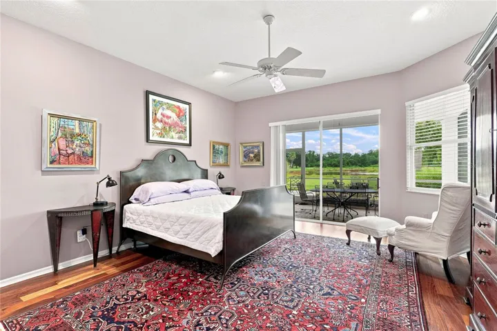 Spacious primary bedroom with hardwood floors, high ceilings and direct lanai access with peaceful backyard views