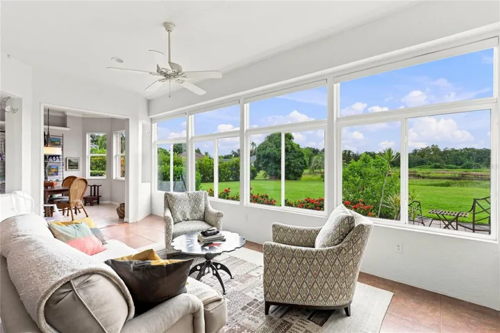 Sun-filled Florida room with expansive windows overlooking the lush backyard and peaceful natural setting