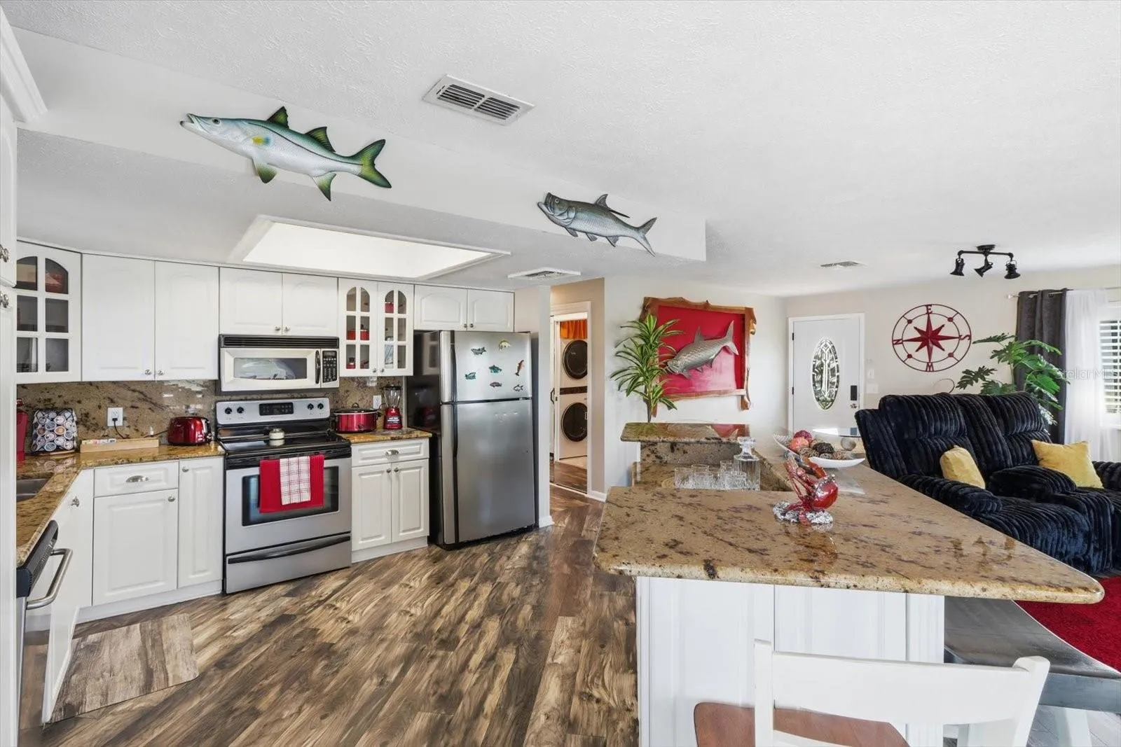 Bright kitchen featuring white cabinetry, extensive countertops, and stainless appliances.