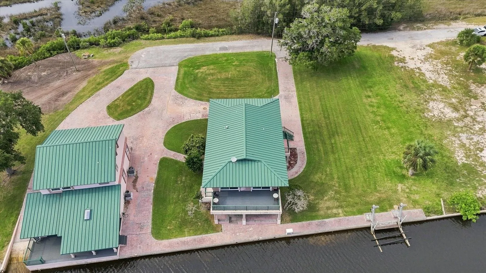 Aerial view showing the residence, detached building, grounds, and waterfront together.