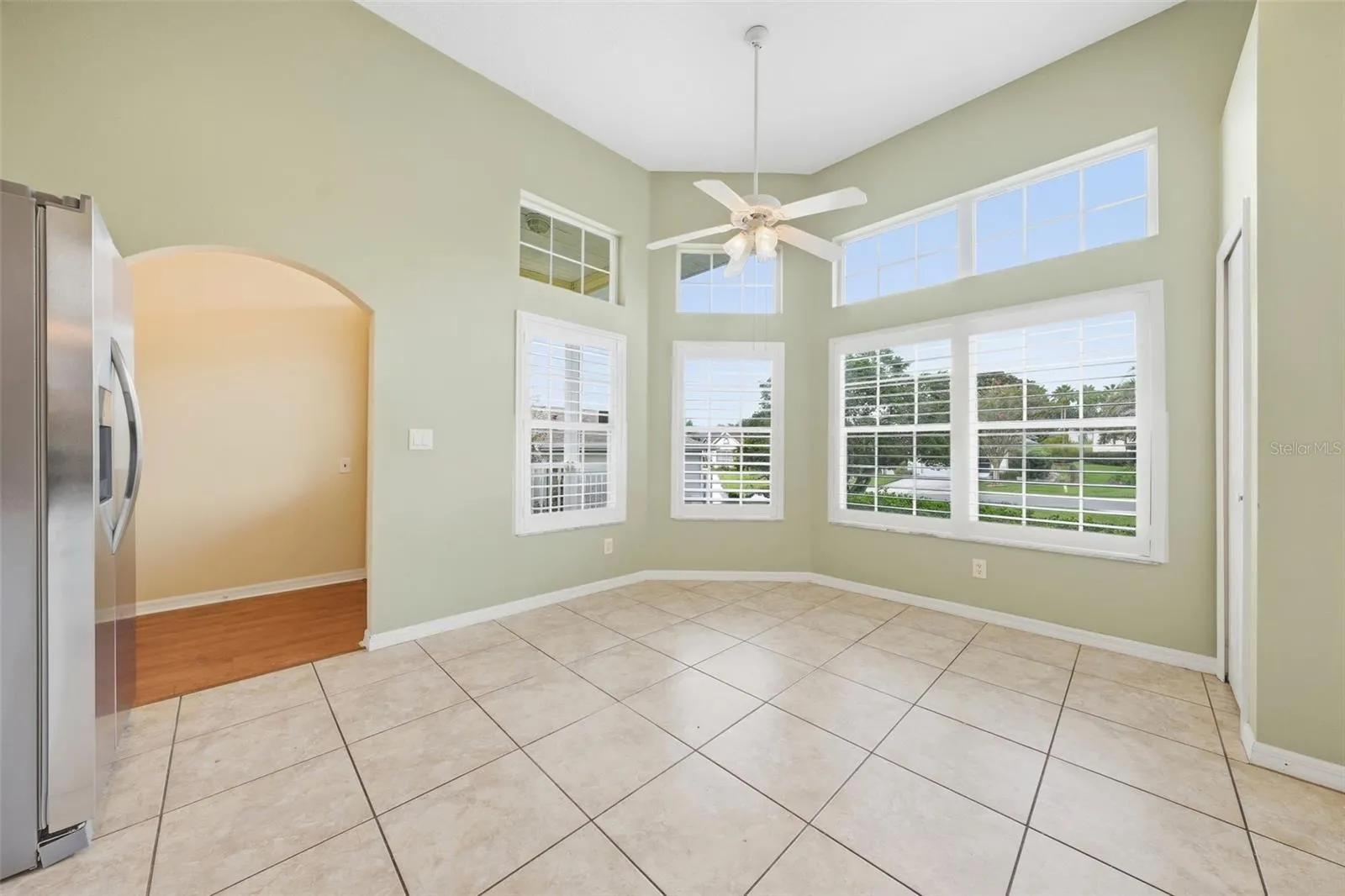 Sun-filled breakfast nook featuring valuted ceilings, expansive windows, and plantation shutters.