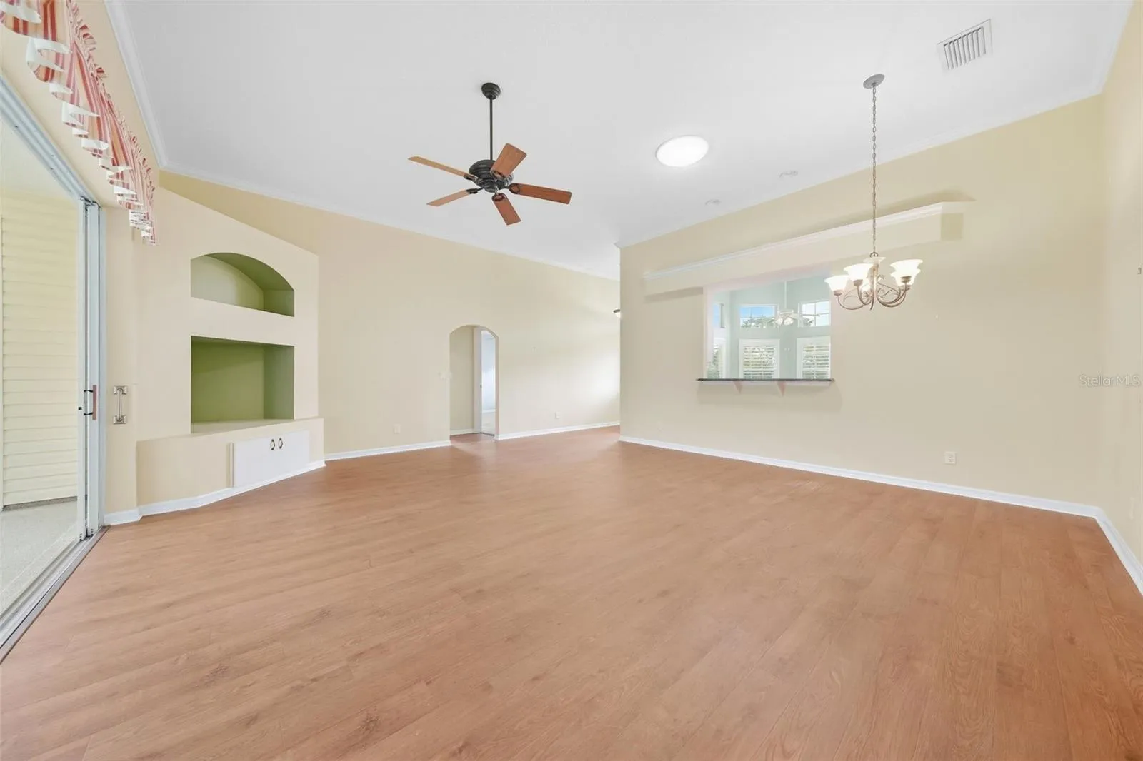 Spacious living area featuring a custome built-in entertainment center with architectural niches and warm wood flooring.