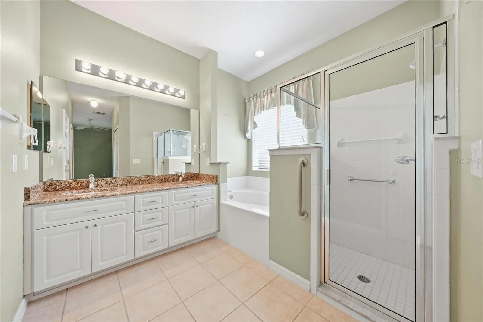 Spacious primary bath with granite vanity, soaking tub, and separate walk-in shower.